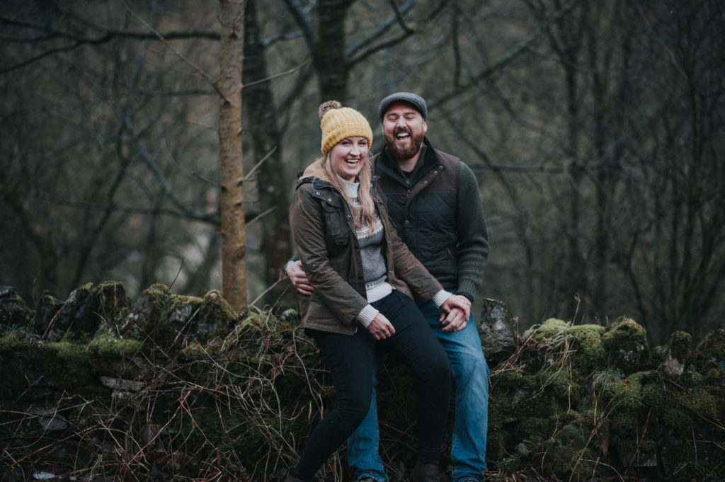 engaged couple sitting on a stone wall in the Peak District