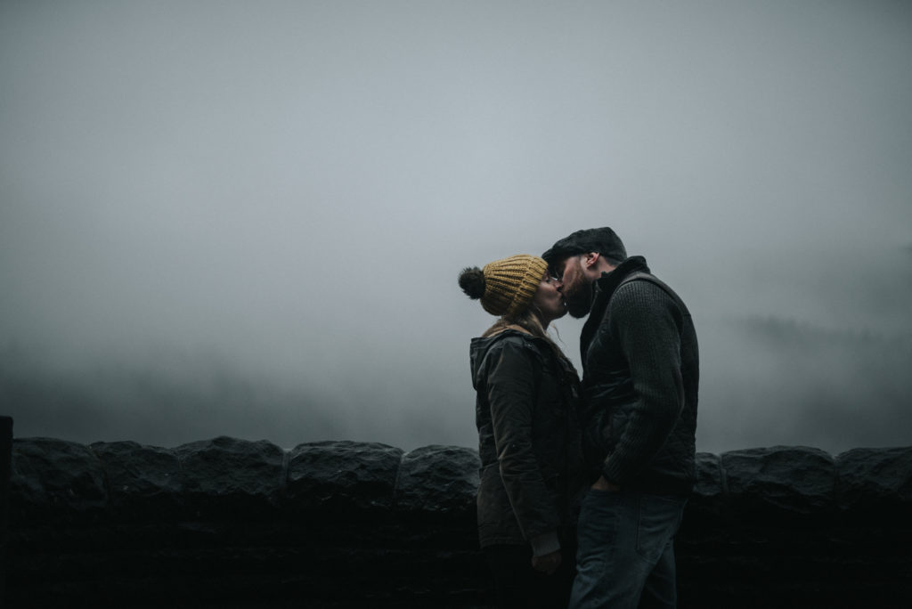 Engagement couple kiss in the mist Lady Bower reservoir