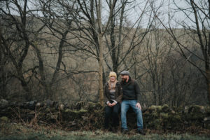 Enagaged couple sat on a stone wall Derbyshire Peak District
